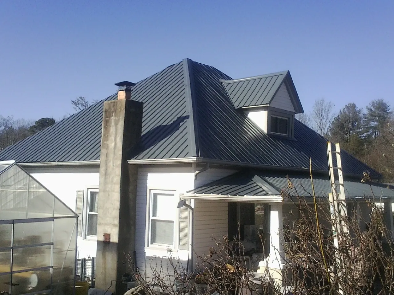Dark blue standing seam metal roof on a white farmhouse with dormer — Slate & Tile Roof Repair by Roofing Brothers in Summit Argo