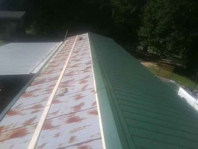 Old rusted panels beside newly installed green metal roofing — Wind Damage Roof Repair by Roofing Brothers in Summit Argo