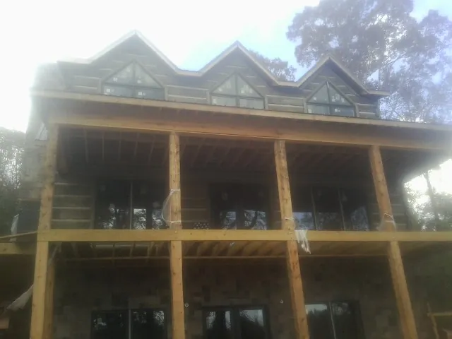 Dormers and porch framing on a large log home under construction — Roof Coating work by our crew in Summit Argo