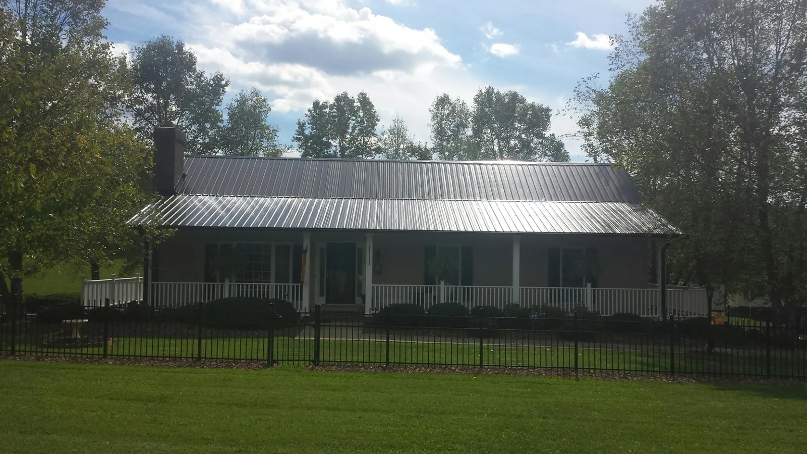 Gray metal roof on a brick ranch with a full width front porch — Gutter Guard Installation work by our crew in Summit Argo